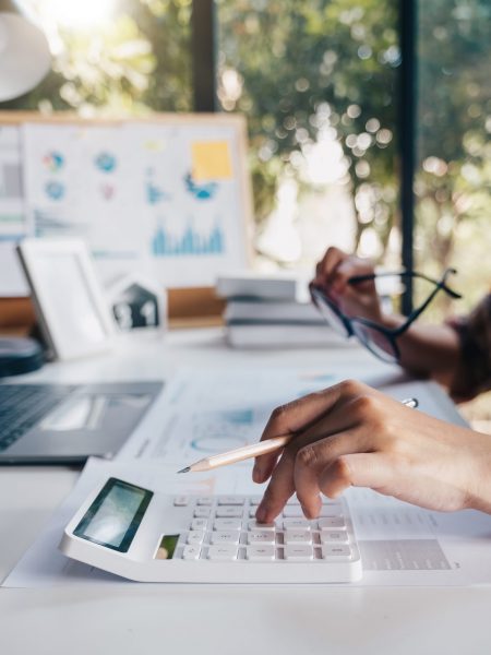 Business woman calculating domestic expenses involved in financial paperwork indoors, focused lady managing monthly banking payments summarizing utility bills and taxes at home.